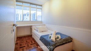 Ein gemütliches Schlafzimmer mit Fenster, einem Bett und einer kleinen Schreibtischzeile.