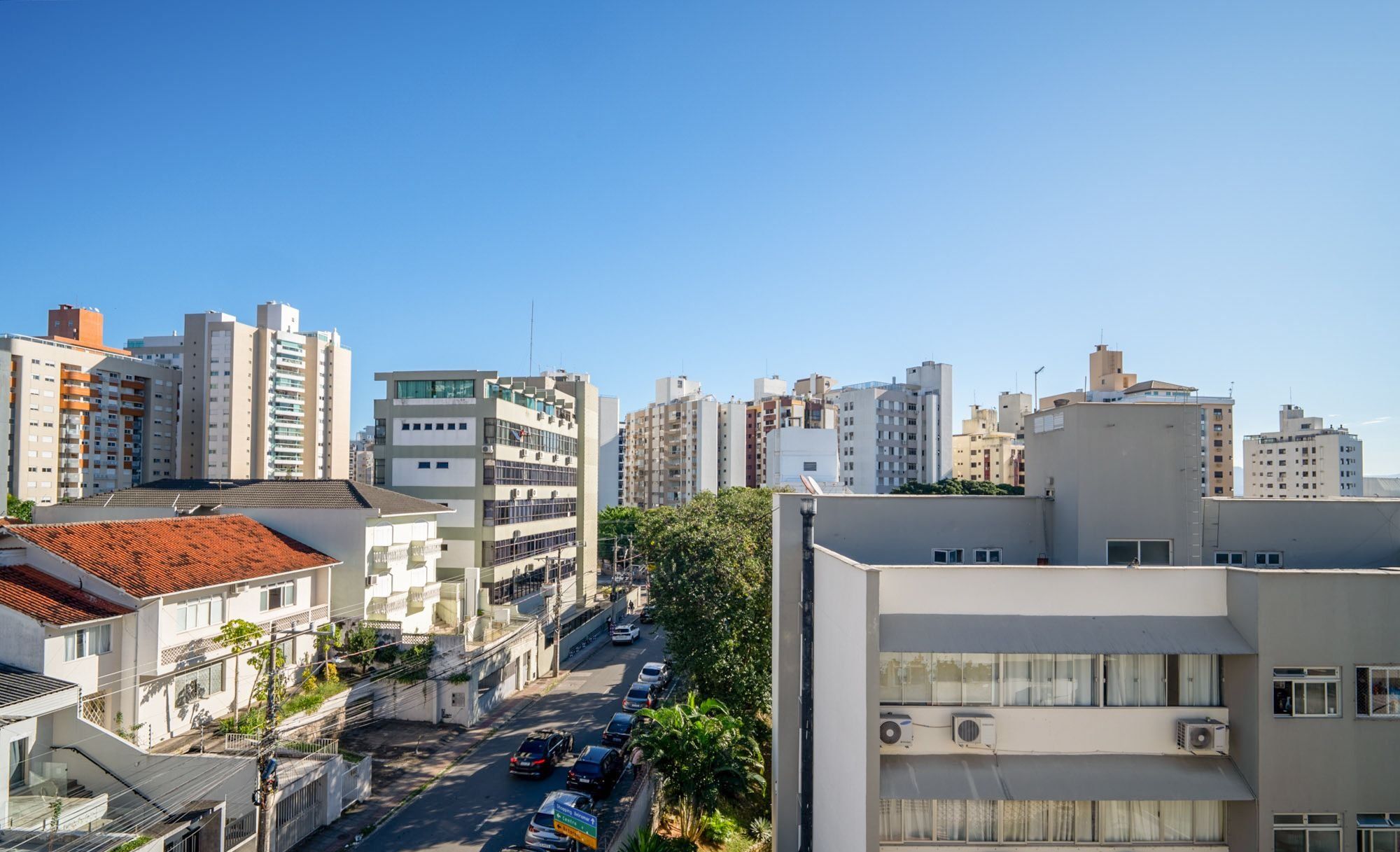 Un horizonte urbano con edificios modernos, cielo despejado y una calle con automóviles estacionados.