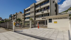 A multi-story building with a gated entrance, a sign indicating a loading area, and a clear sky. - Apartment With Home Office in Floripa Jfm0062 (Florianópolis)