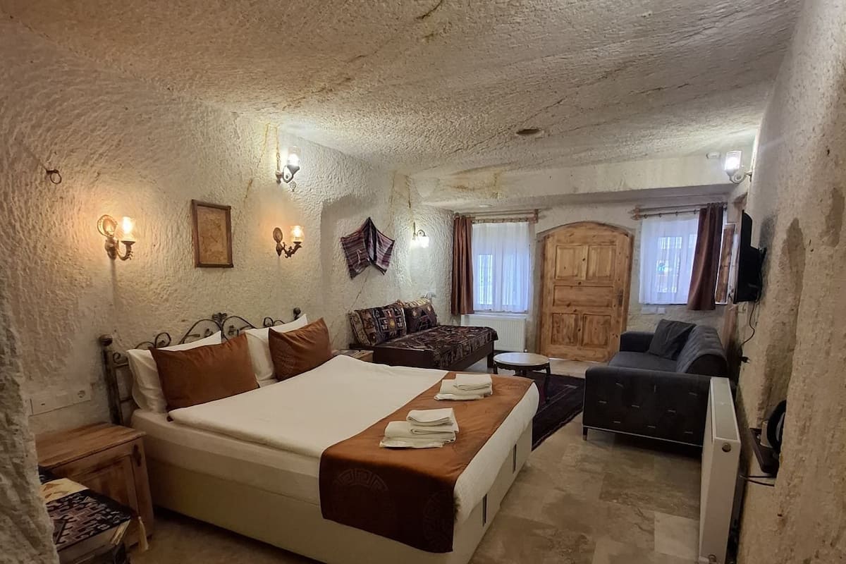 A bedroom with a bed, bedside tables, a small desk, a sofa, and a wardrobe.