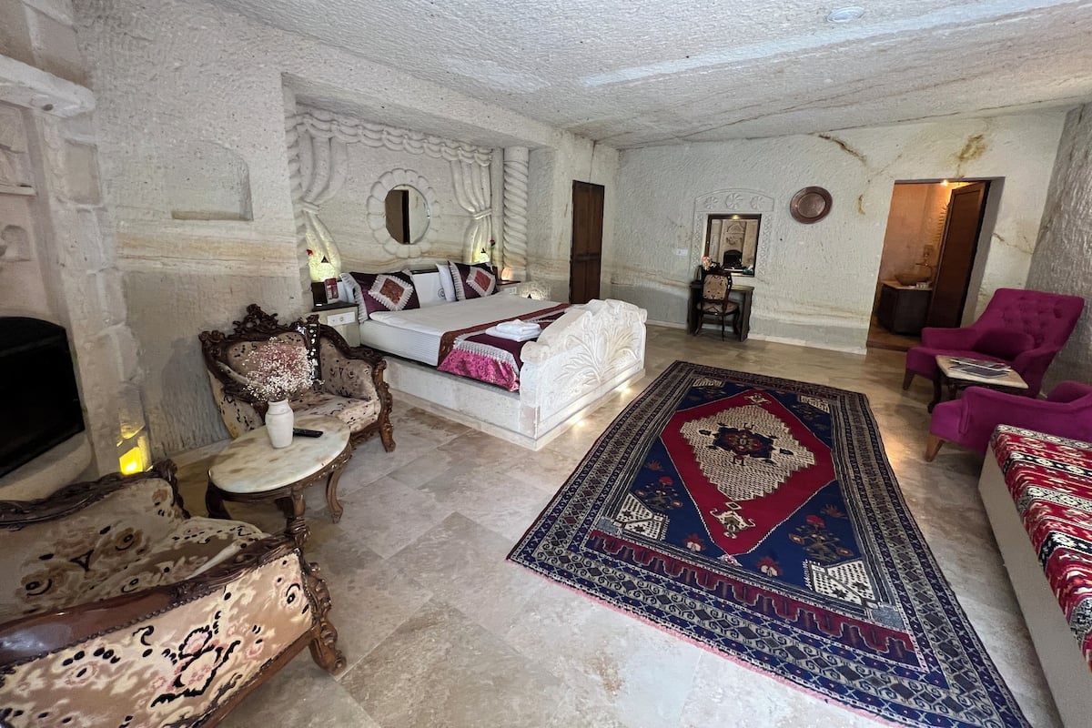 A spacious room with a large bed, a desk, a chair, and a sofa.