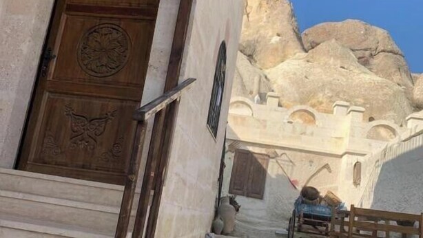 Un edificio de piedra con un letrero de recepción, una puerta de madera con adornos y un patio empedrado con piedra.