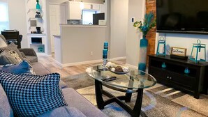 Un salon moderne avec une table basse en verre, un canapé et un téléviseur.