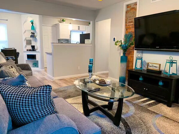 A modern living room with a glass coffee table, a sofa, and a TV.