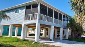 A two-story house with a balcony, a covered porch, and a palm tree in the background.