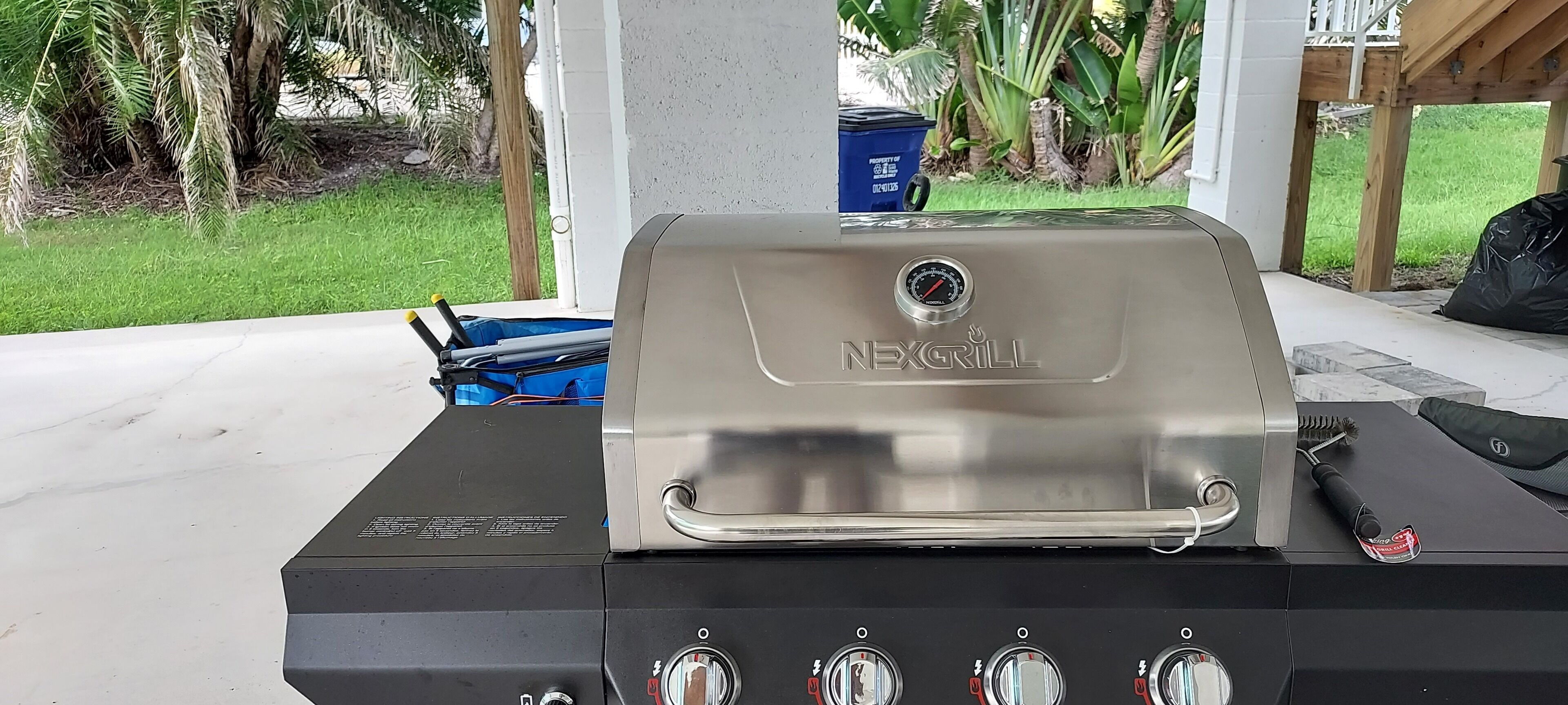 A NEXGRILL barbecue grill with four control knobs, a digital display, and a stainless steel lid.