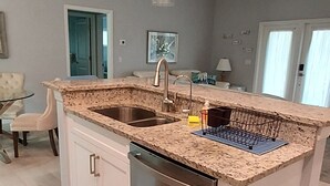 Eine moderne Küche mit Granit Arbeitsplatten, Edelstahlgeräten und Pendelleuchten.