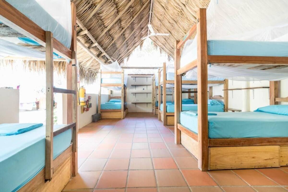A corridor with bunk beds, wooden frames, and a tiled floor.