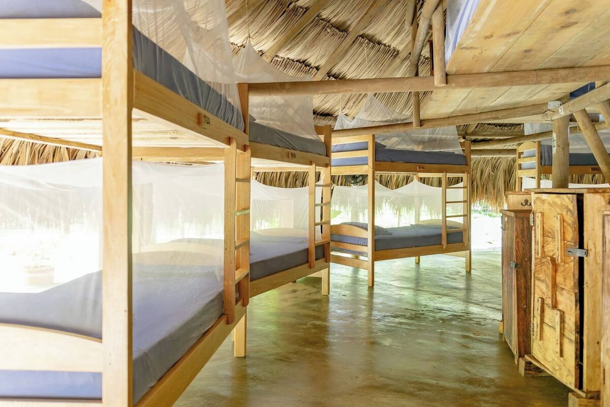 A room with bunk beds, a wooden cabinet, and a thatched roof.