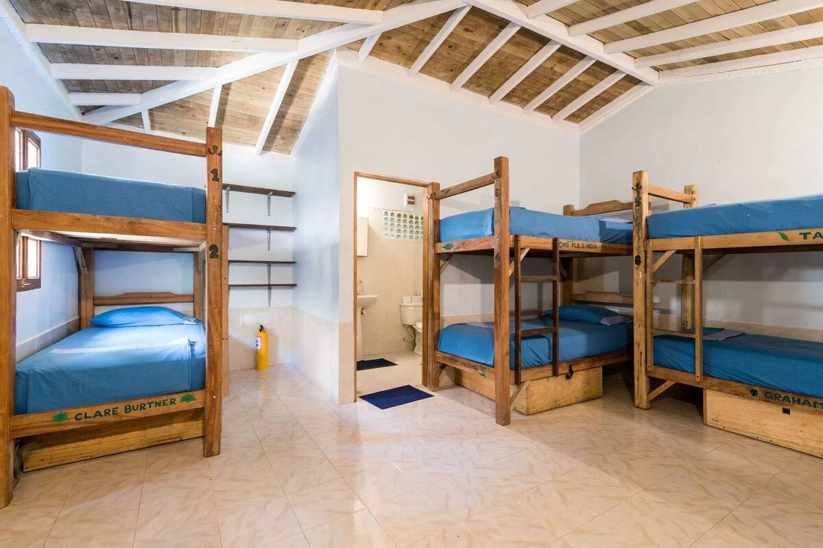 A dormitory room with bunk beds, a small bathroom, and a tiled floor.