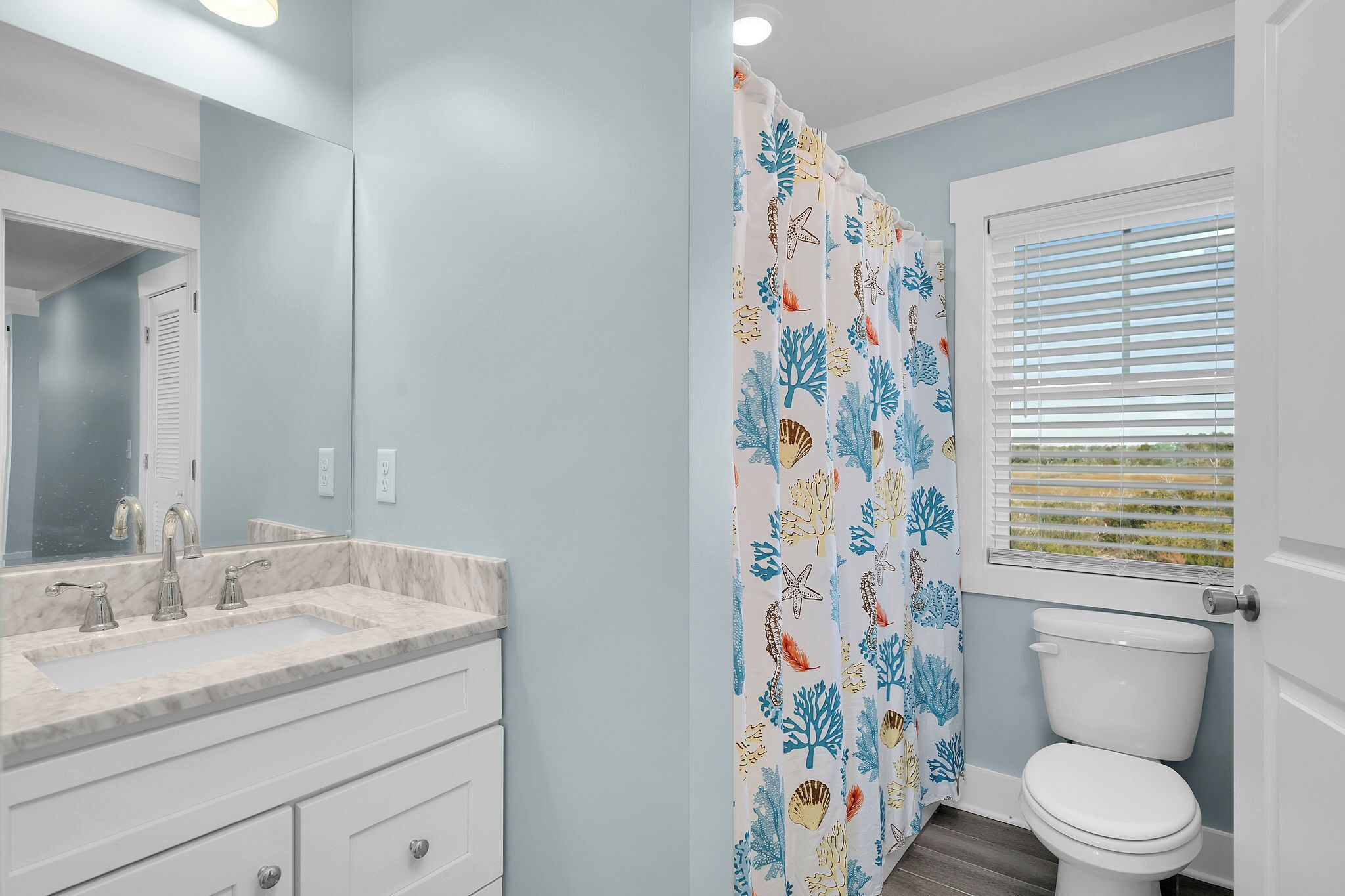 A bathroom with a white sink, mirror, and toilet.
