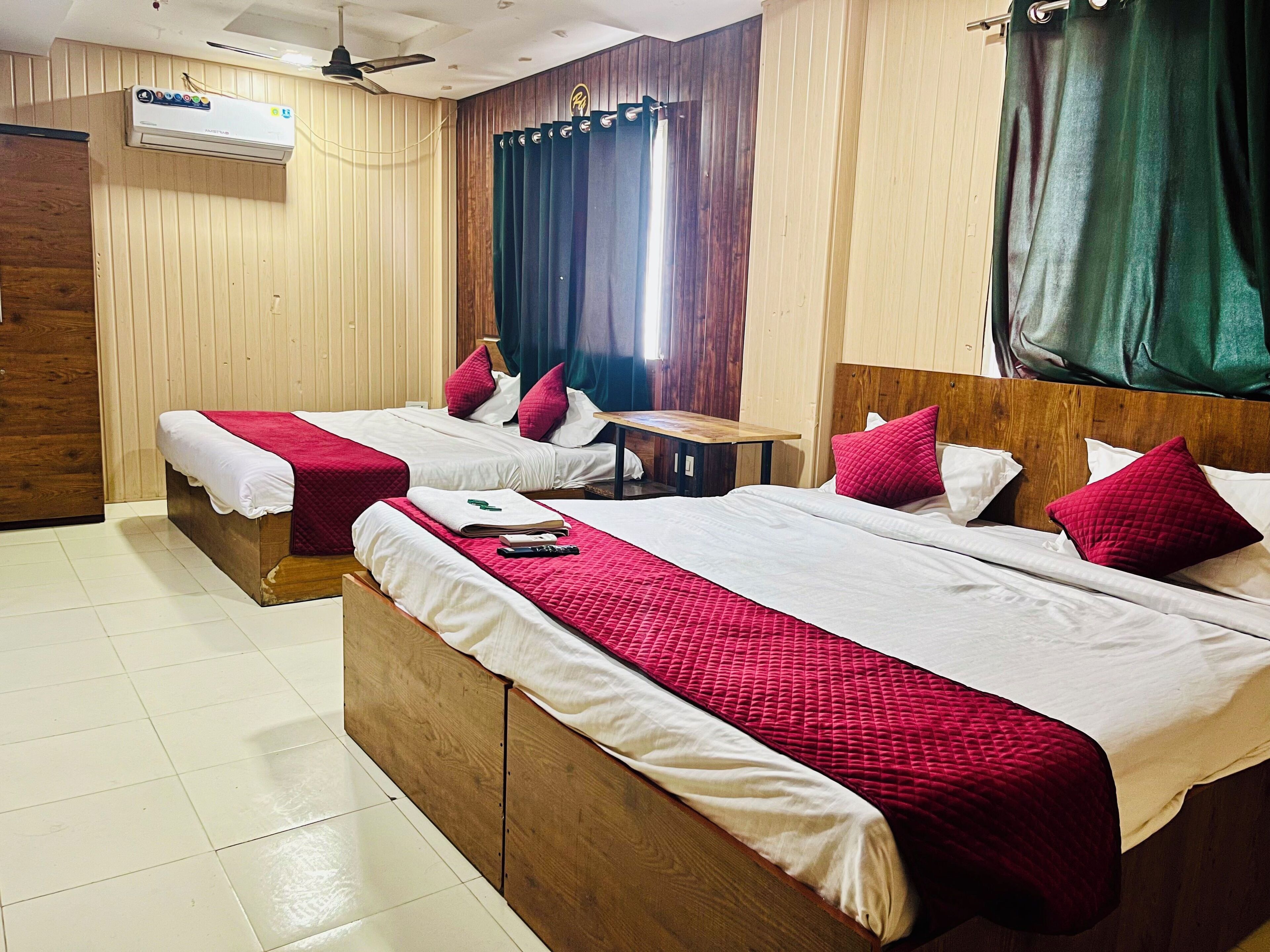 A hotel room with two wooden beds, a desk, and a window with curtains.