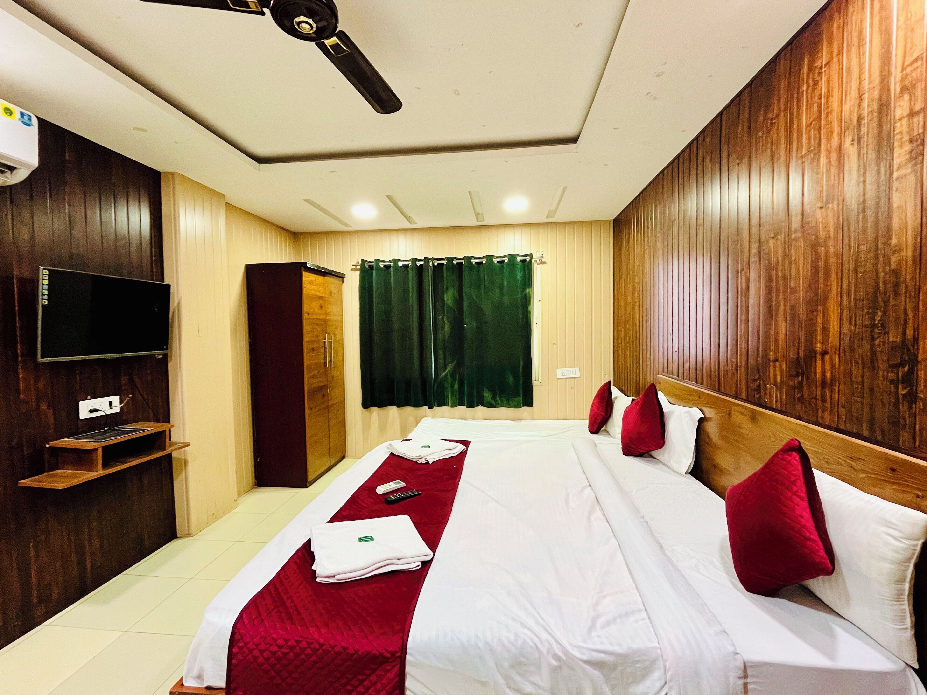 Une chambre d’hôtel équipée d’un lit, d’une télévision, d’une armoire et d’un ventilateur de plafond.