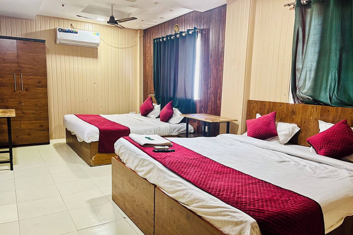 A hotel room with two beds, wooden headboards, a small table, and a ceiling fan.