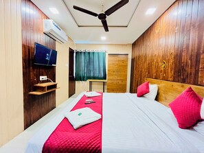 A hotel room with a bed, a TV, a ceiling fan, and a wardrobe.