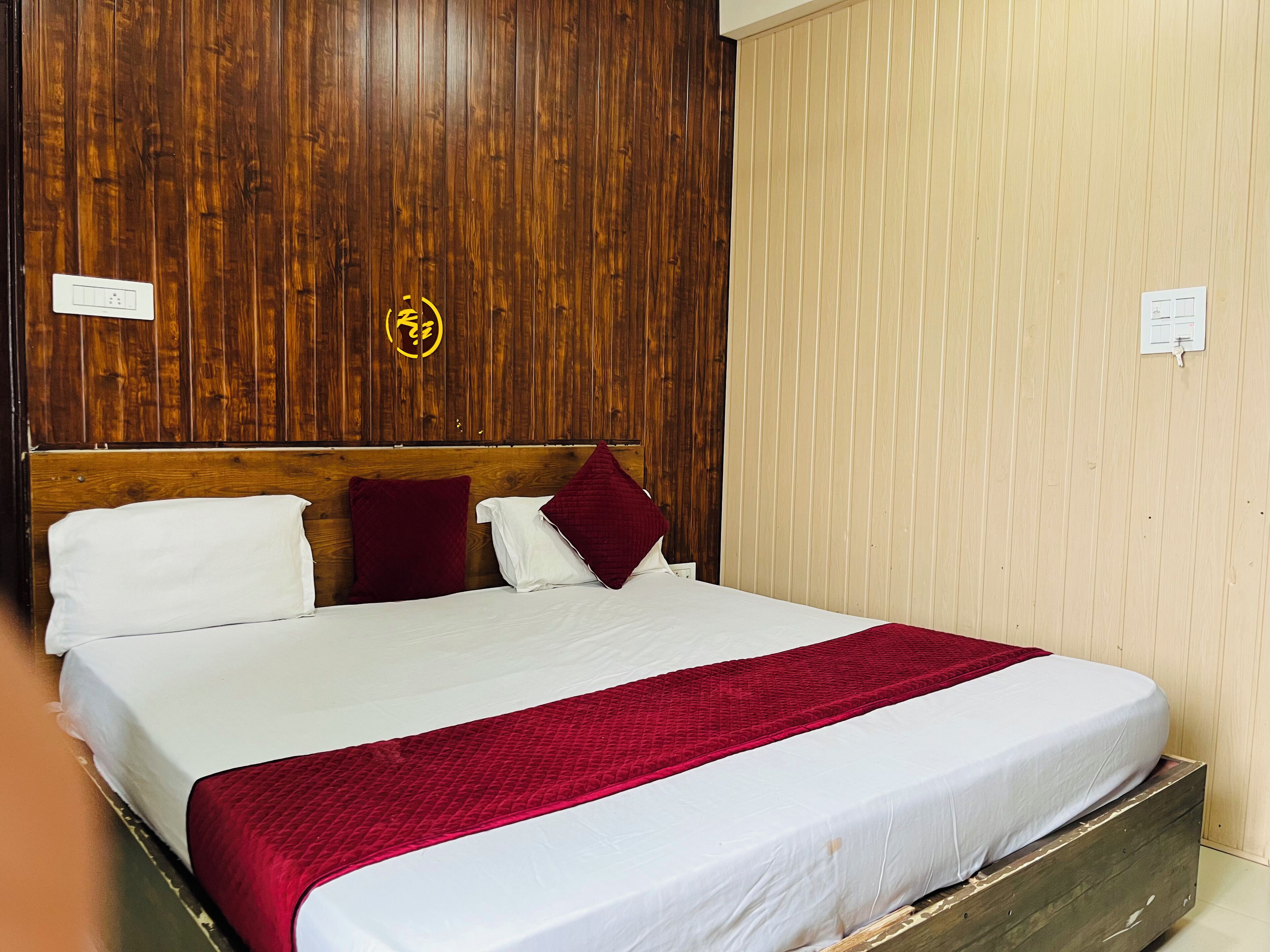 Una cama con sábanas blancas, un edredón acolchado rojo y dos almohadas.