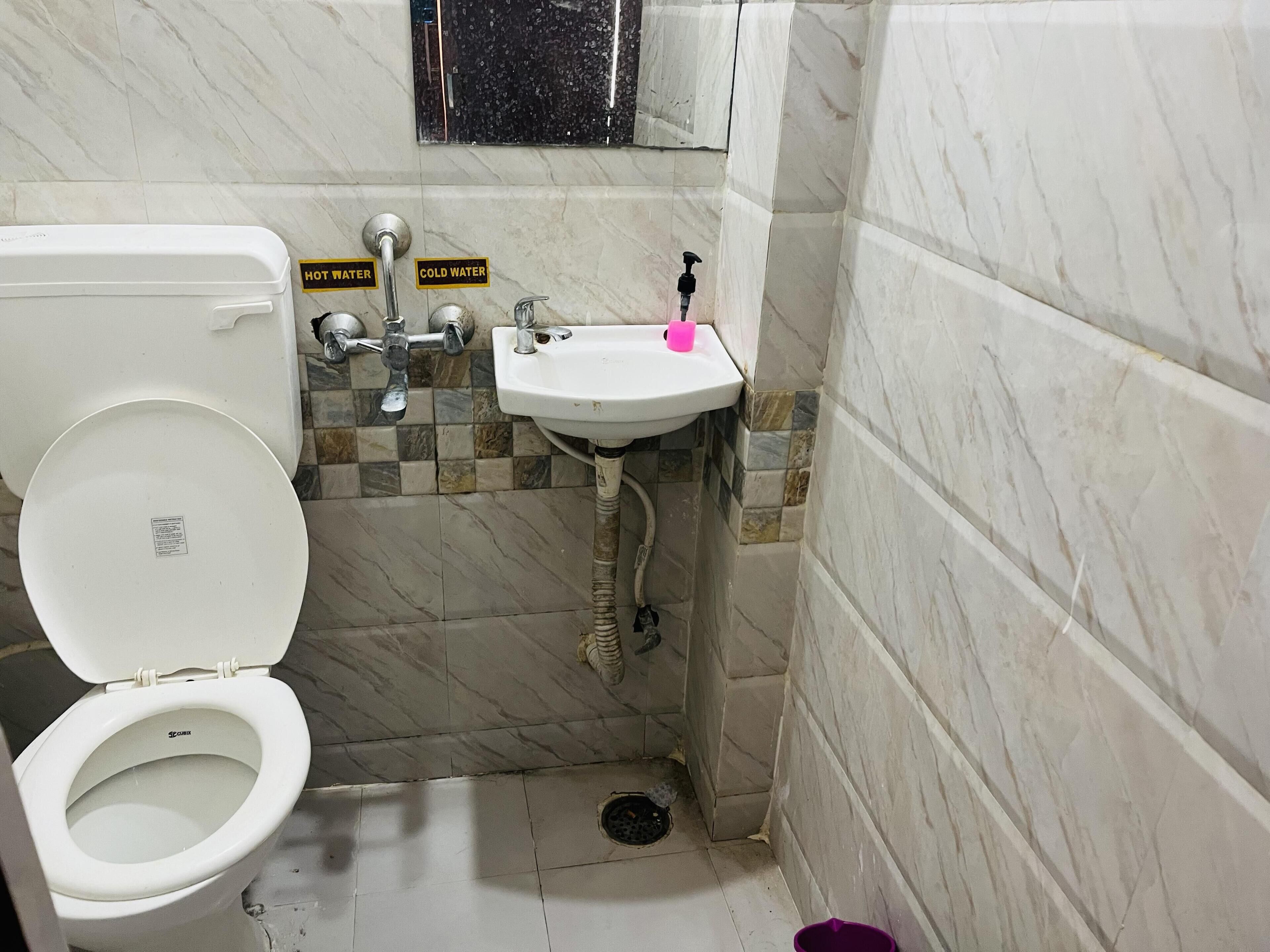 A small bathroom with a toilet, sink, and shower.