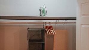 A closet with a hanging rack, a shelf, and an iron on the top shelf. - Dream / King Bed / 120" Projector / Canopy Bed (Philadelphia)