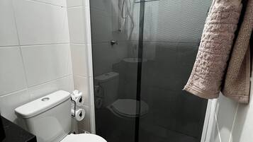 Een douche, handdoeken, zeep, toiletpapier