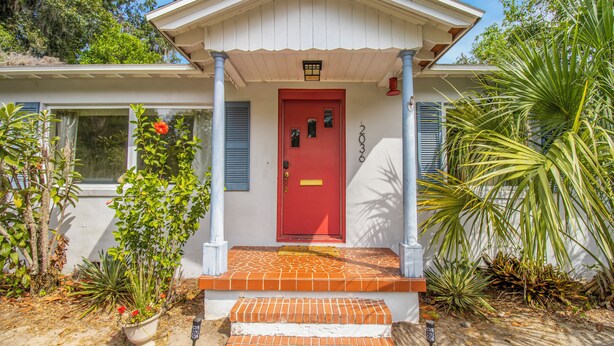 A house with a red door, white exterior, and a covered porch. - Private Pool Paradise w/ Games Galore! Less than a mile to Stadium & O'Dome! (Gainesville)