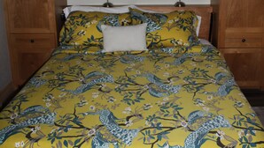 A bed with a floral bedspread, two bedside lamps, and wooden headboard and footboard.