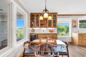 A kitchen with wooden cabinets, a glass dining table, and a view of the outdoors.