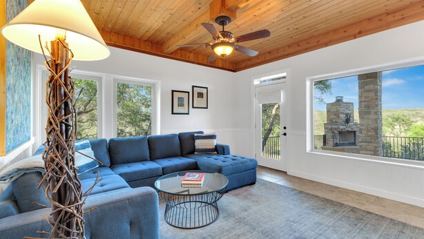 A modern living room with a sectional sofa, a glass coffee table, and a ceiling fan.