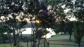 A fenced area with trees and a body of water in the background.