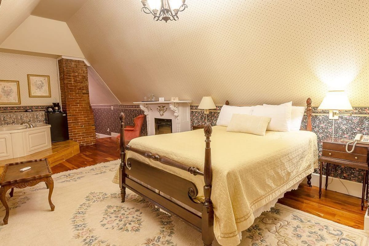 Un dormitorio con cama, mesita de noche, lámpara y chimenea.