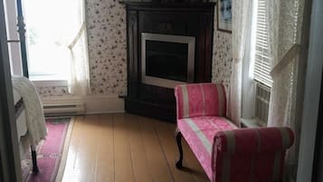 Una habitación con chimenea, un sillón rosa y una alfombra estampada.