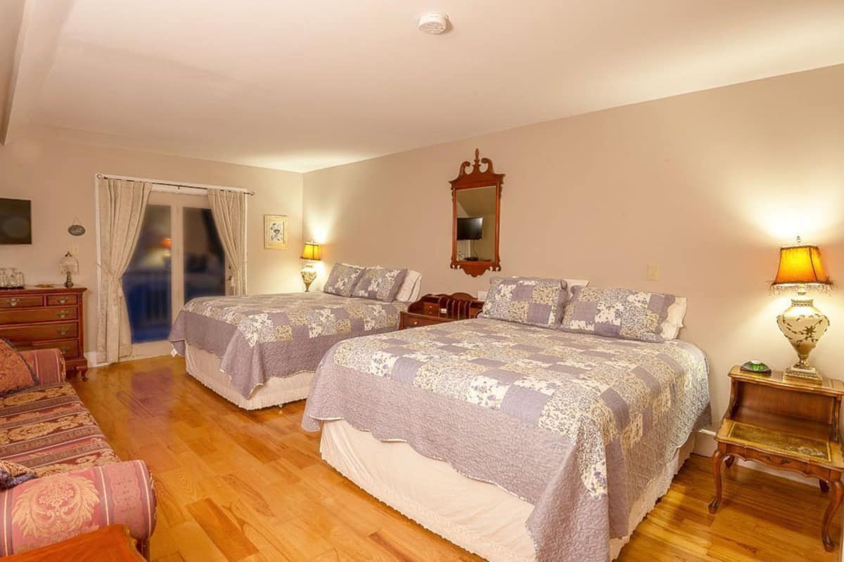 Un dormitorio con dos camas, un sofá, un aparador y un espejo.