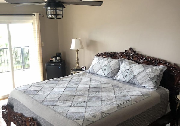 A neatly made bed with a patterned bedspread and pillows, a bedside lamp, and a ceiling fan. - St. Martins Country Inn (St. Martins)