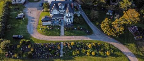 An aerial view of a large, two-story house with a prominent front porch and a driveway leading to the entrance.