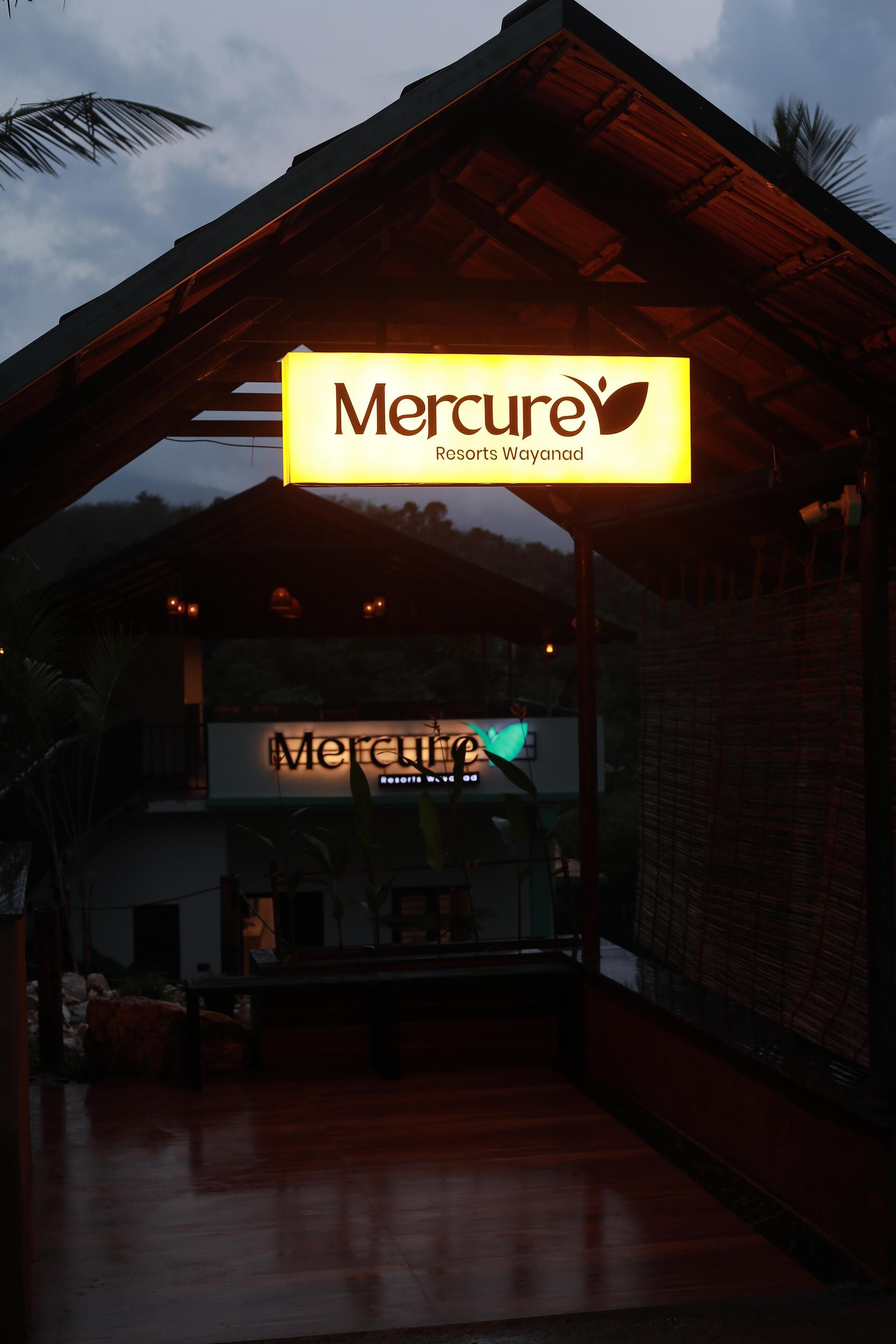 A Mercure Resort Wayanad sign illuminated in yellow.