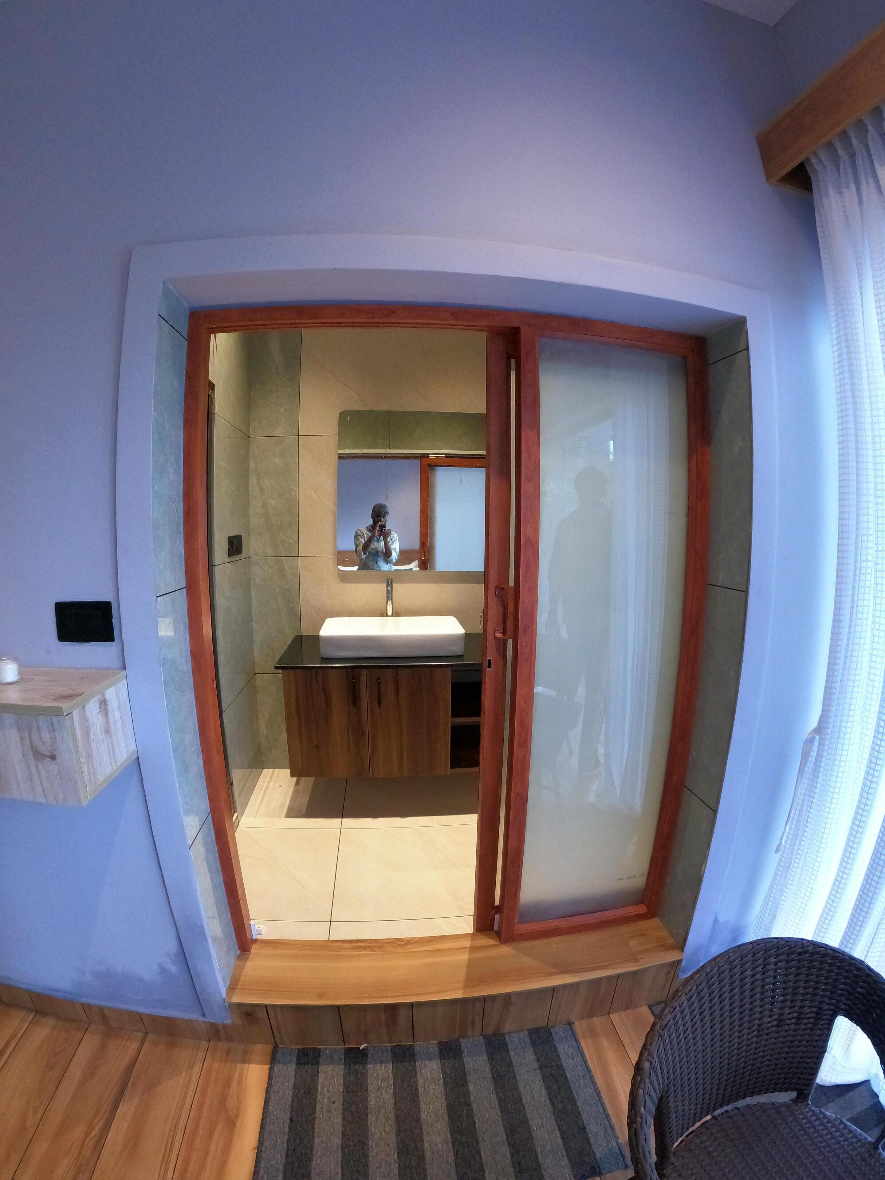 Une salle de bain moderne avec un meuble-lavabo en bois, un grand miroir et une cabine de douche en verre.