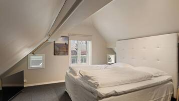 A bedroom with a large bed, a window, and a TV.