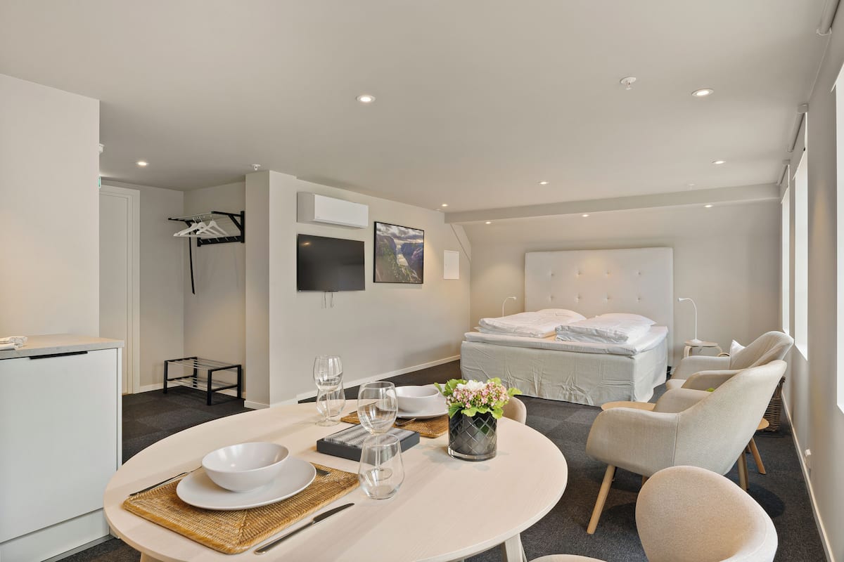 A modern hotel room with a dining area, a bed, and a TV.