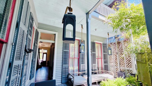 A covered porch with a wooden deck, outdoor seating, and hanging lanterns.