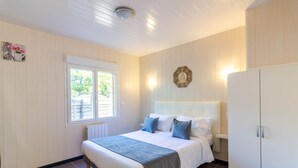 Ein Schlafzimmer mit Bett, Fenster, Kleiderschrank und Wandlampe.