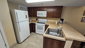 A compact kitchen with a refrigerator, microwave, stove, and sink.