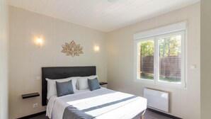 Een slaapkamer met een bed, nachtkastjes, een raam en een wandlamp.