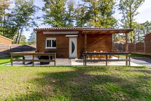 A small wooden cabin with a patio area, a door, and a window. - Authentic Stay in Dordogne – Comfortable Gîte with Heated Pool (Thenon)