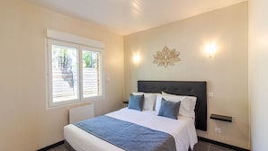 A bedroom with a bed, a window, a wall-mounted light, and a decorative wall piece. - Authentic Stay in Dordogne – Comfortable Gîte with Heated Pool (Thenon)