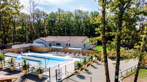 A pool area with lounge chairs, a wooden deck, and a building with a red-tiled roof. - Authentic Stay in Dordogne – Comfortable Gîte with Heated Pool (Thenon)