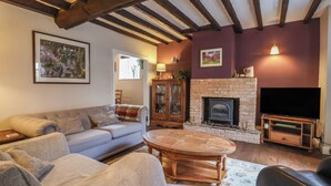 Un salón acogedor con chimenea, un sofá, una mesa de centro y un televisor.