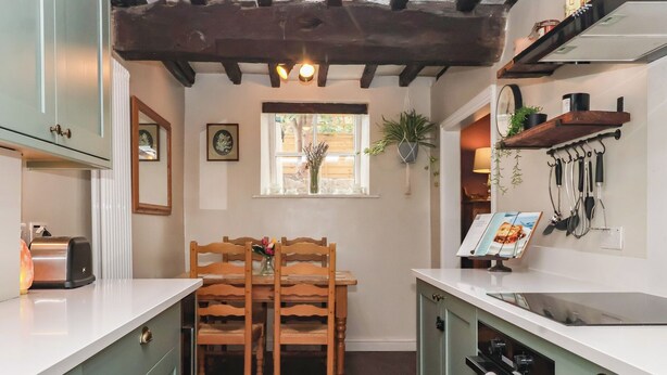 Una cocina con sillas de madera, una mesa de comedor y una ventana con plantas.