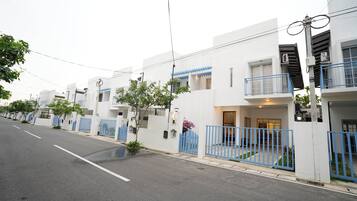 Una hilera de edificios blancos modernos con balcones azules y entradas protegidas por portones.