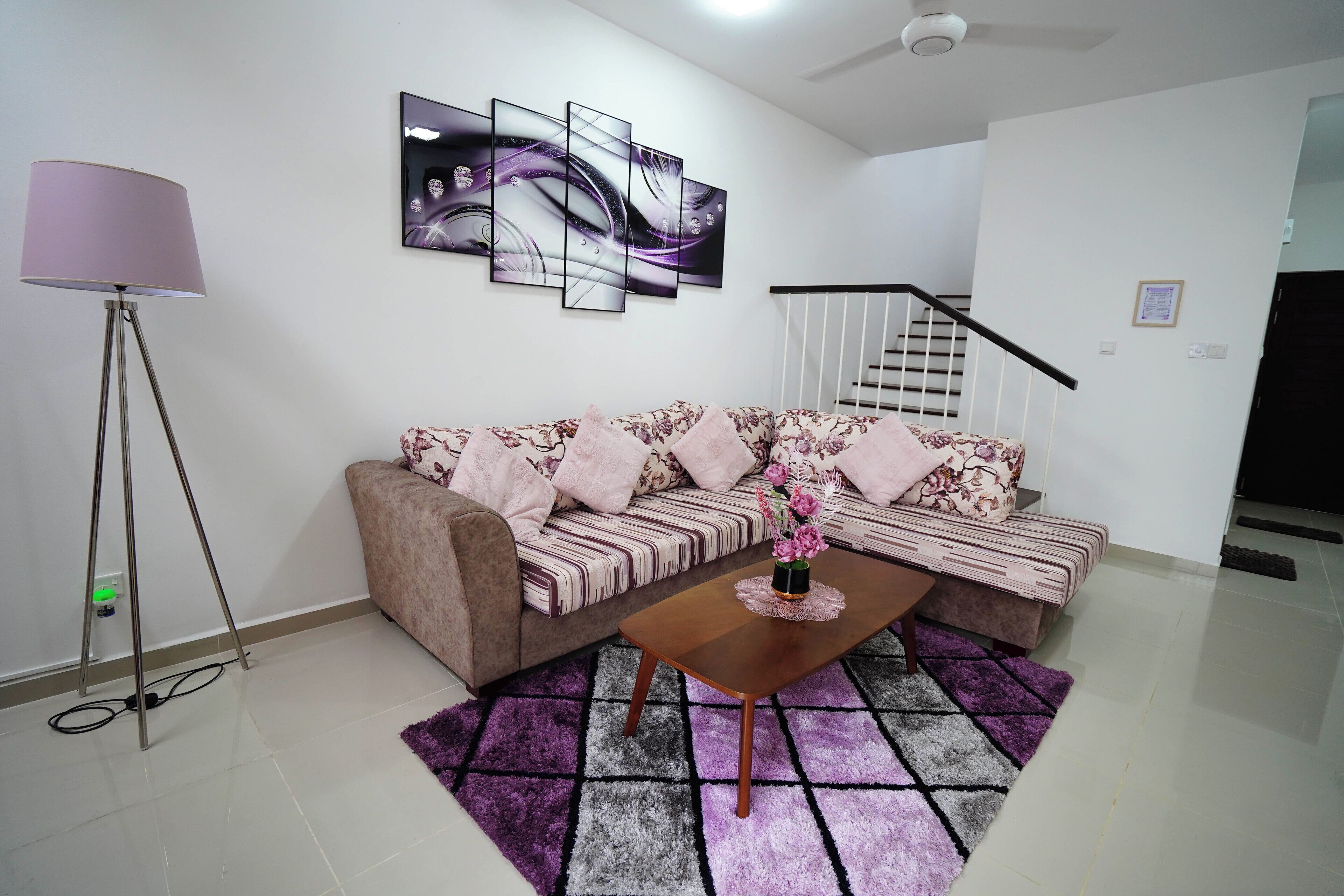 A living room with a sofa, a coffee table, a floor lamp, and a staircase.