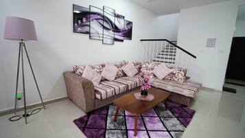 A living room with a sofa, a coffee table, a floor lamp, and a staircase.