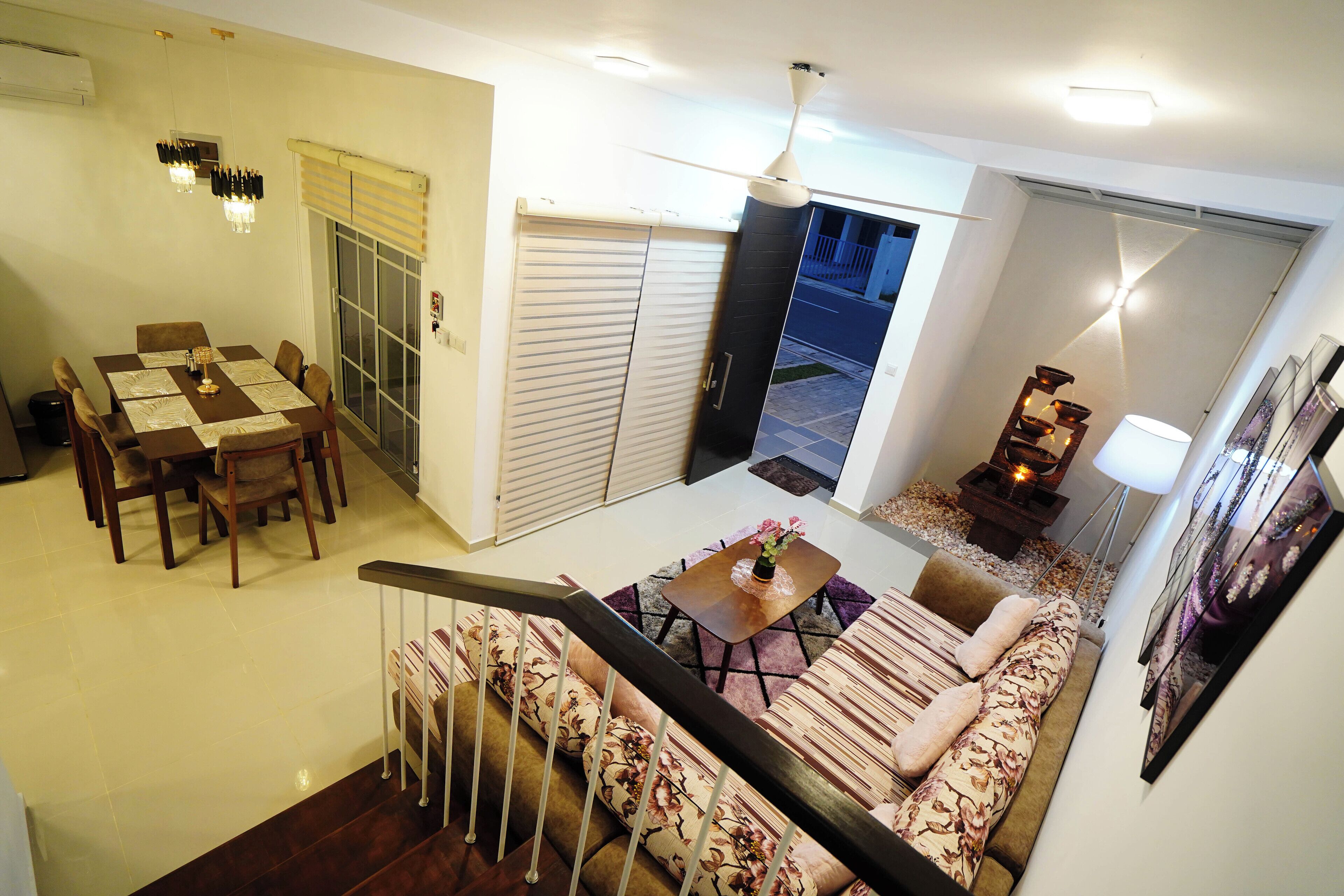 A spacious living area with a sofa, a dining table, and a staircase.